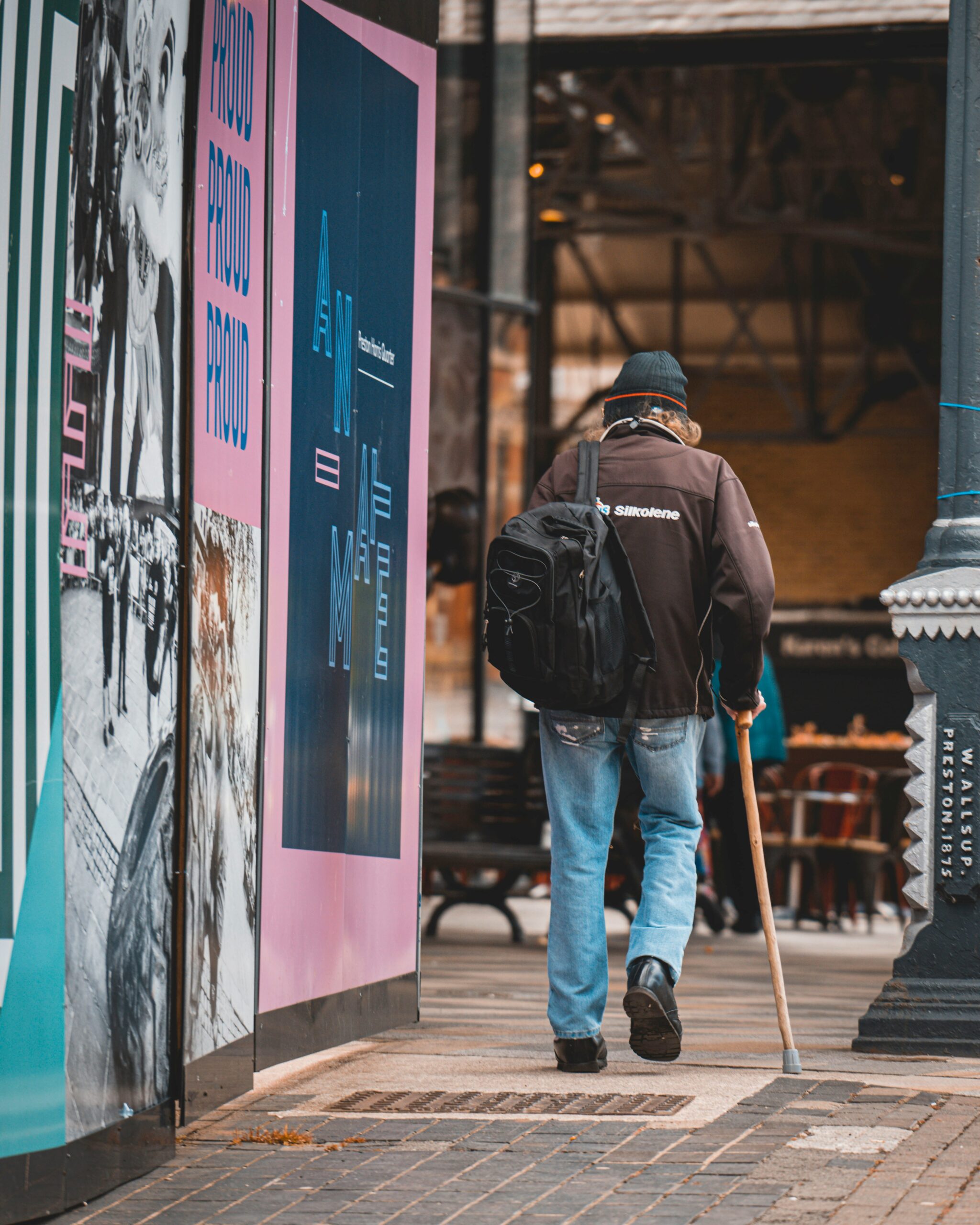 A man walks away using a cane in an urban setting.