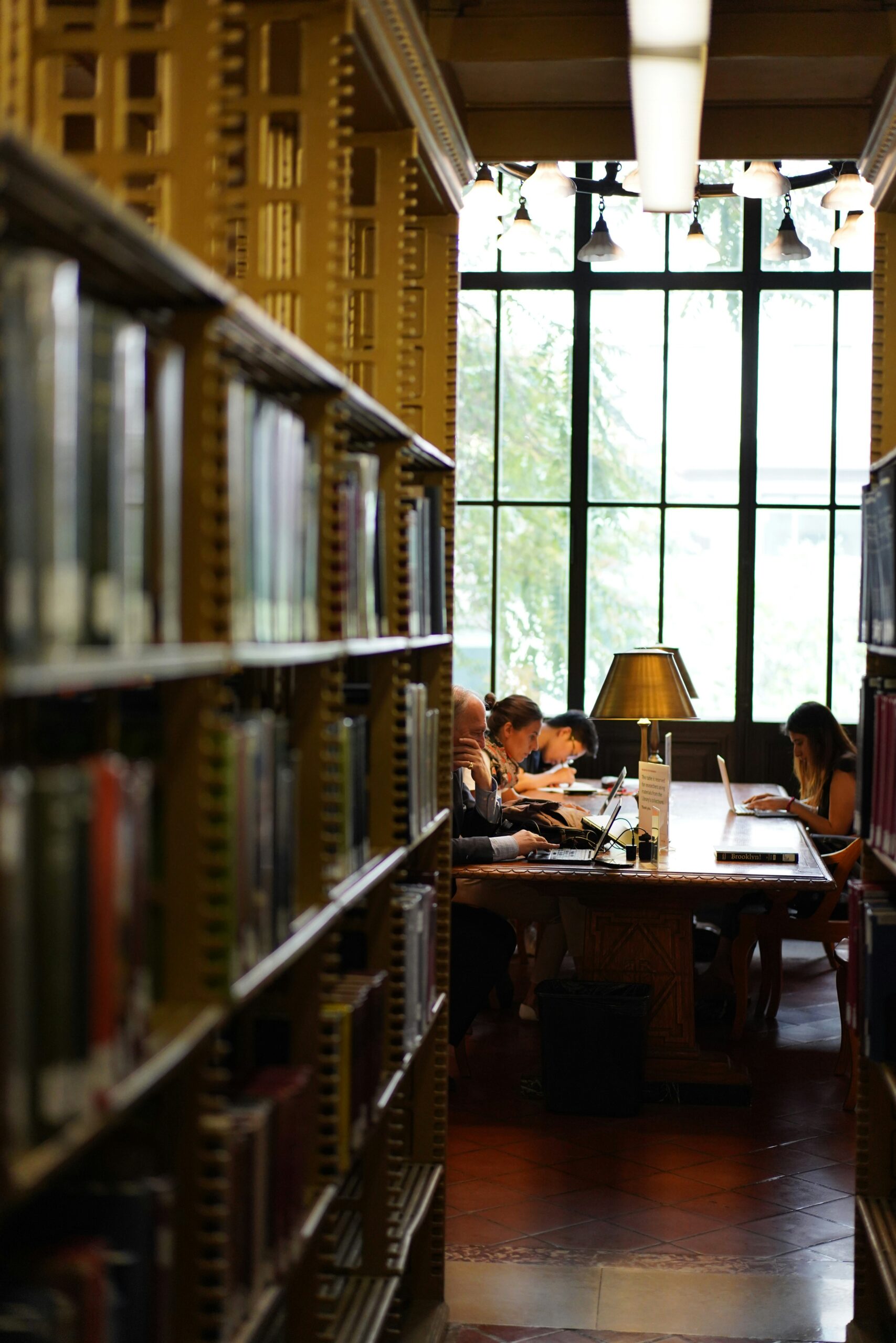 People sitting at a brown wooden table in a library