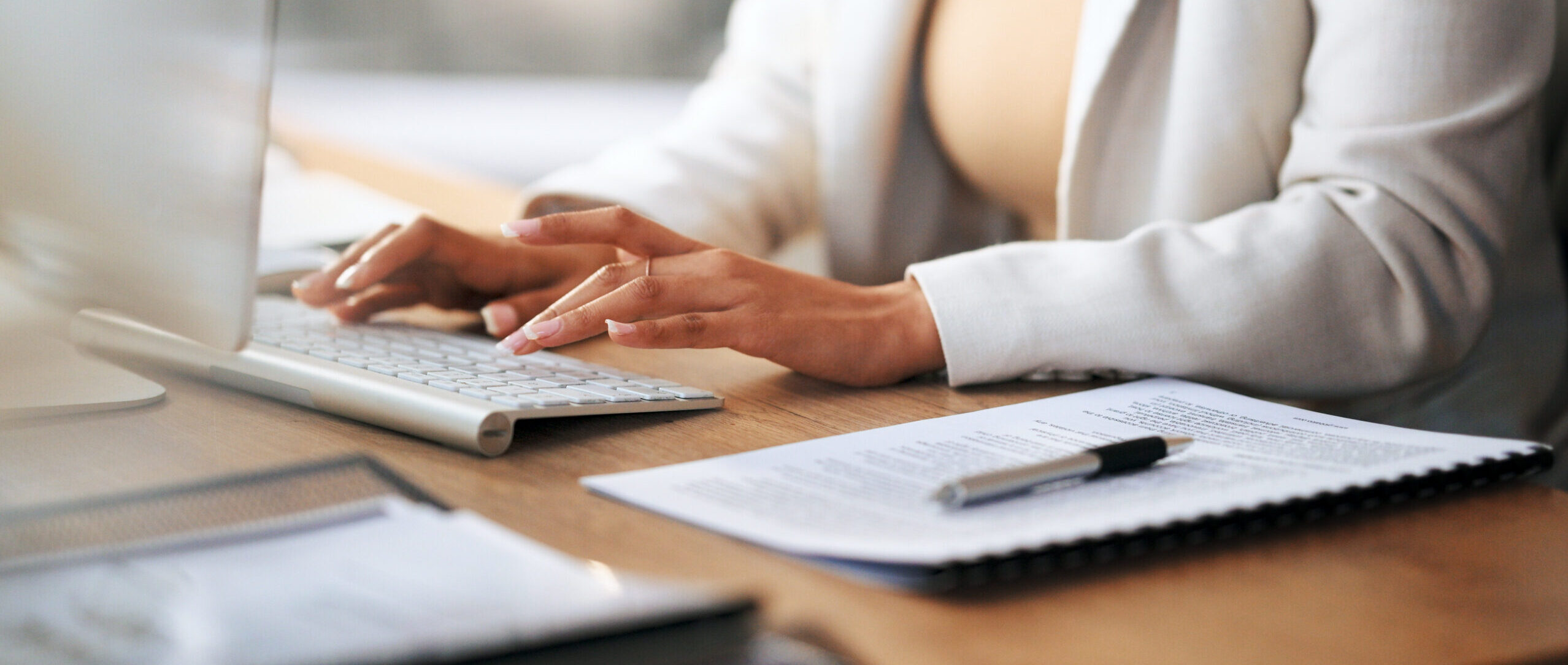 Closeup of the hands of a receptionist typing and sending emails while working in an office alone. One secretary doing admin and writing reports while organizing a schedule for her manager at work